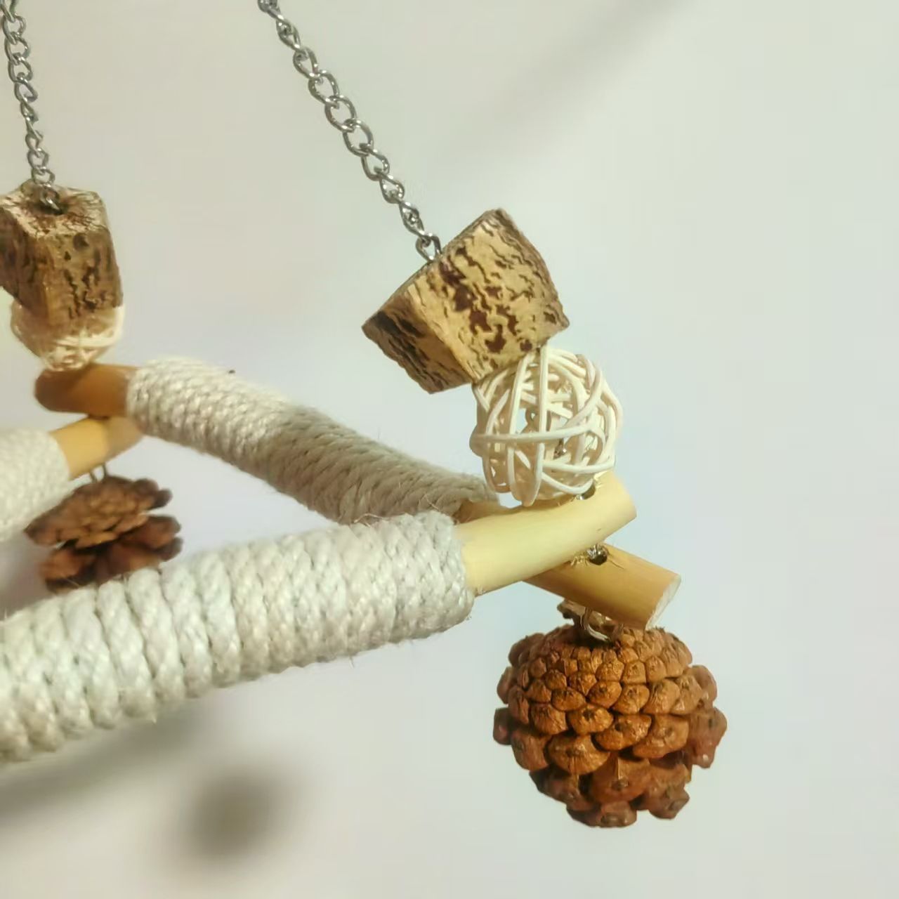 A large bird swing with a cage for chewing toys, 3 bird pads wrapped in sisal, and a stable triangular design, a wooden hanging toy swing (small)